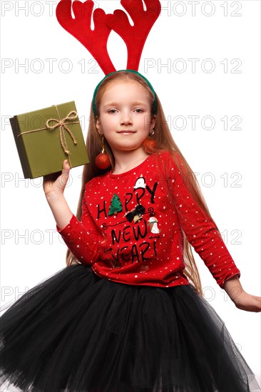 Beautiful little girl in a New Year's image with boxes of gifts in hands and deer horns on her head. Photo taken in the studio