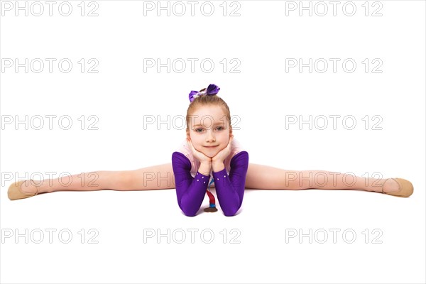 Little girl gymnast with a medal in a sports swimsuit doing exercises. Photo taken in the studio on a white background