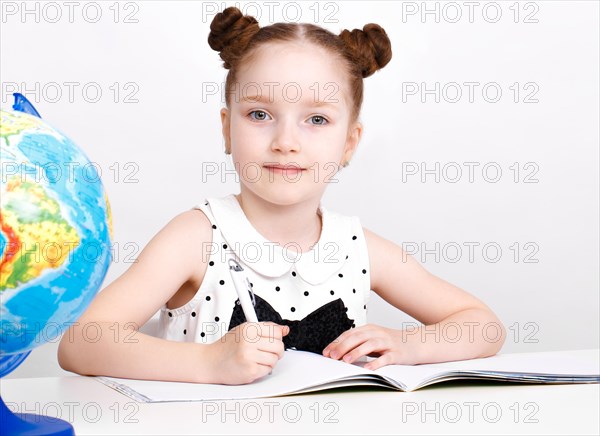 Little girl at the table of a first-grader. Photo taken in the studio