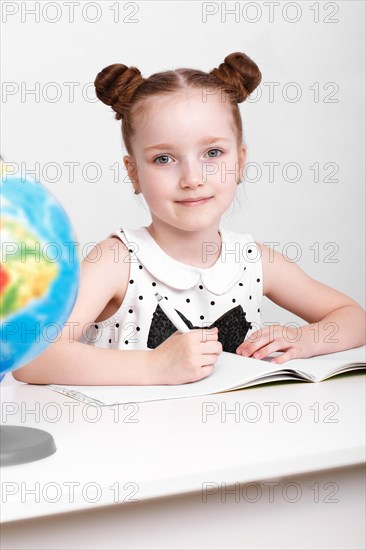 Little girl at the table of a first-grader. Photo taken in the studio