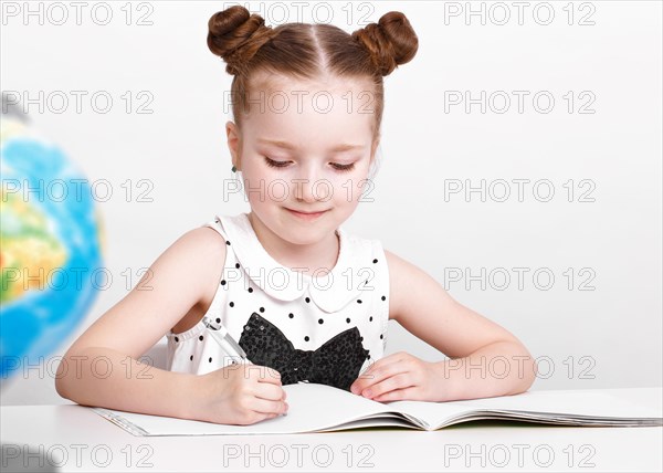 Little girl at the table of a first-grader. Photo taken in the studio