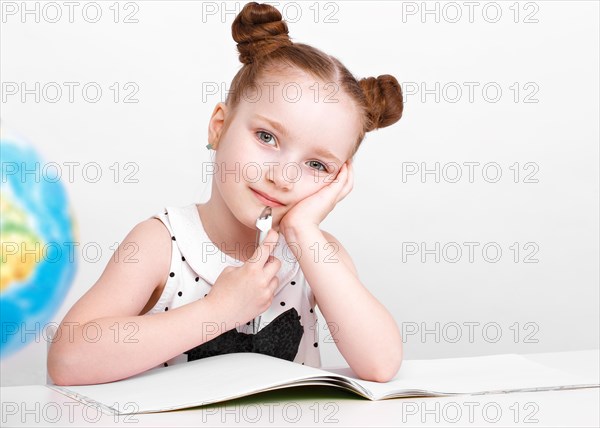 Little girl at the table of a first-grader. Photo taken in the studio