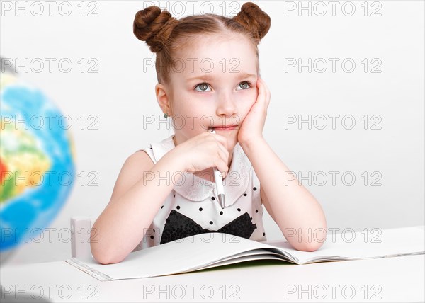 Little girl at the table of a first-grader. Photo taken in the studio