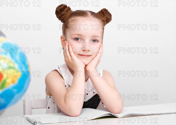 Little girl at the table of a first-grader. Photo taken in the studio