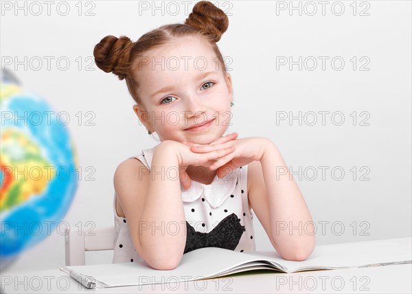 Little girl at the table of a first-grader. Photo taken in the studio
