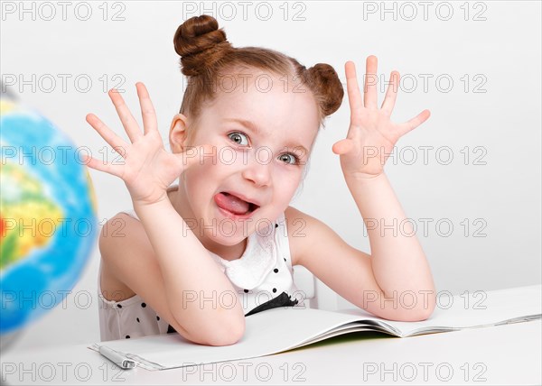 Little girl at the table of a first-grader. Photo taken in the studio