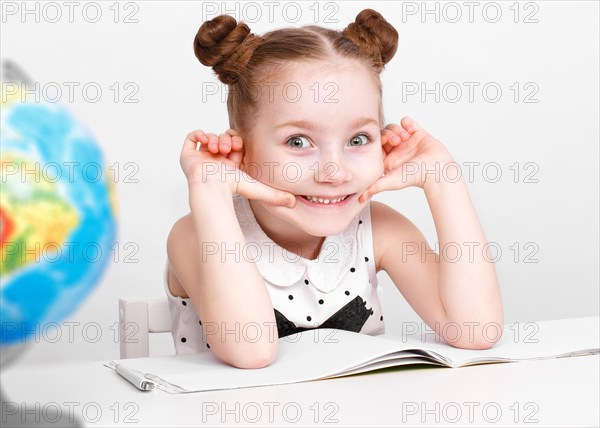 Little girl at the table of a first-grader. Photo taken in the studio