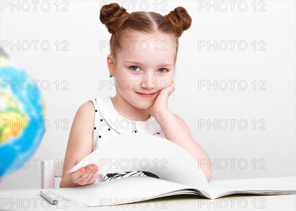 Little girl at the table of a first-grader. Photo taken in the studio