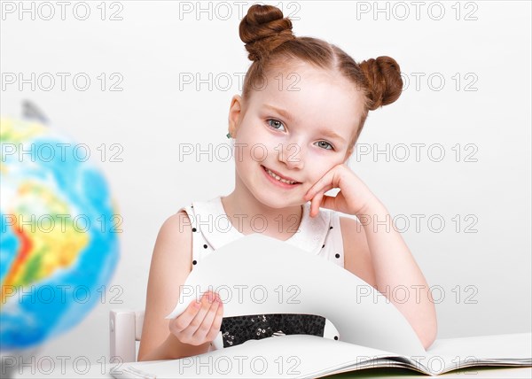 Little girl at the table of a first-grader. Photo taken in the studio