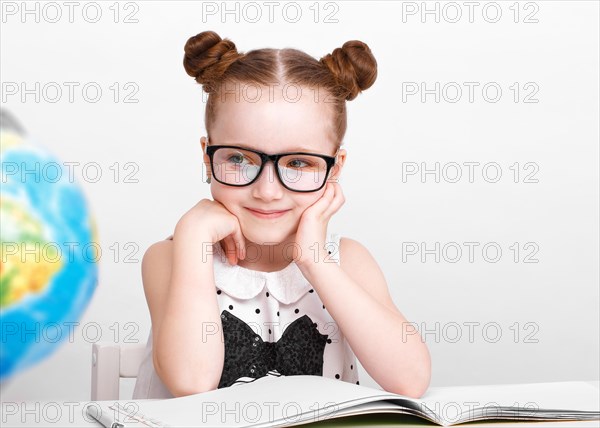 Little girl at the table of a first-grader. Photo taken in the studio