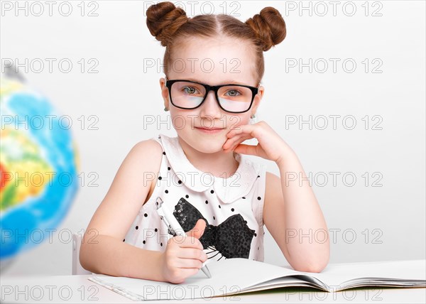 Little girl at the table of a first-grader. Photo taken in the studio