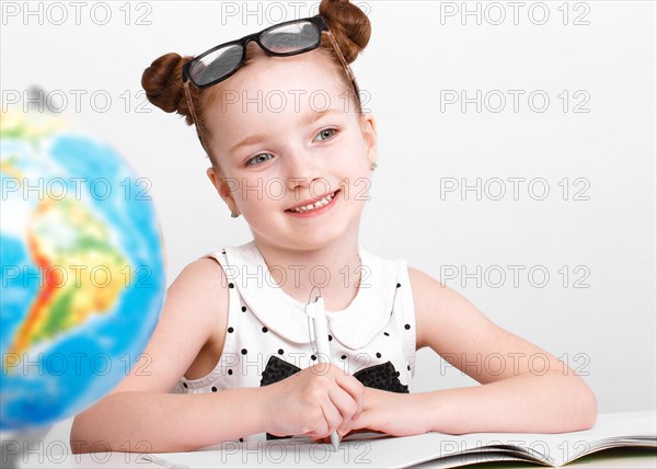 Little girl at the table of a first-grader. Photo taken in the studio