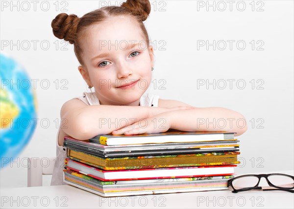 Little girl at the table of a first-grader. Photo taken in the studio