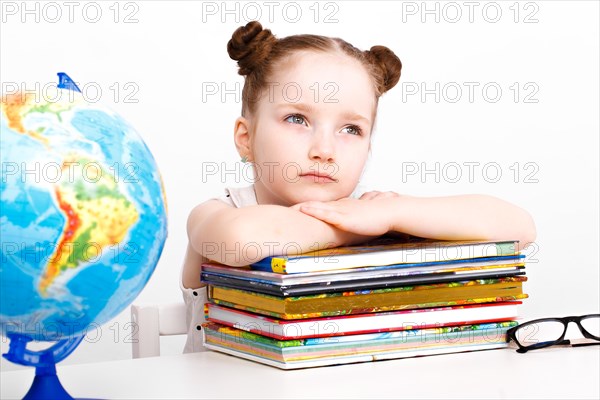 Little girl at the table of a first-grader. Photo taken in the studio