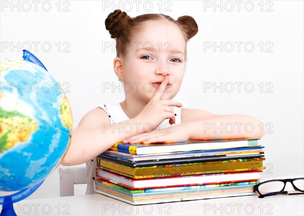 Little girl at the table of a first-grader. Photo taken in the studio