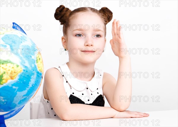 Little girl at the table of a first-grader. Photo taken in the studio