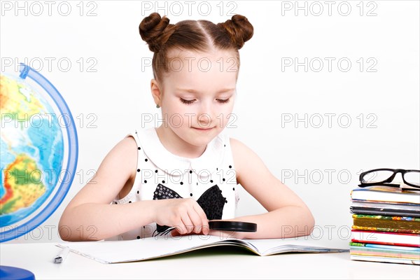 Little girl at the table of a first-grader. Photo taken in the studio