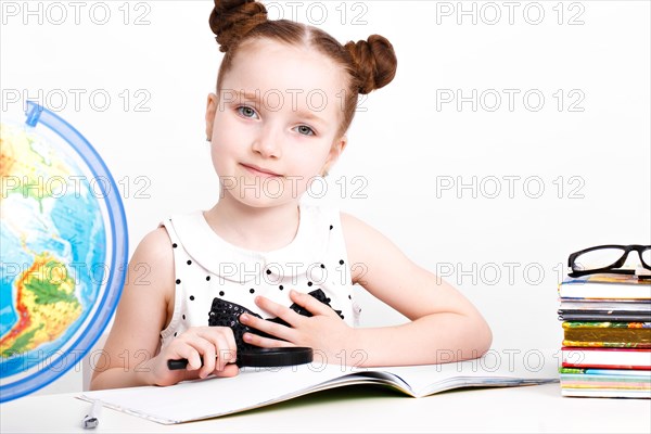 Little girl at the table of a first-grader. Photo taken in the studio