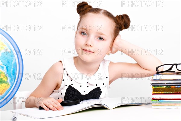 Little girl at the table of a first-grader. Photo taken in the studio