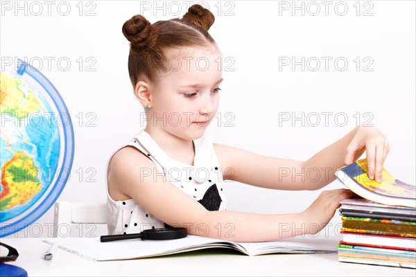 Little girl at the table of a first-grader. Photo taken in the studio