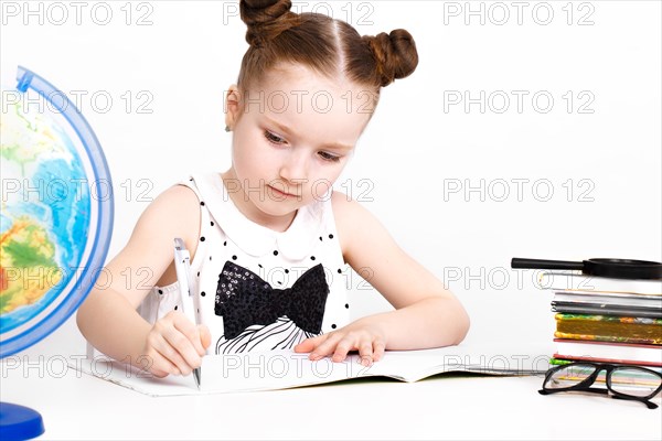 Little girl at the table of a first-grader. Photo taken in the studio