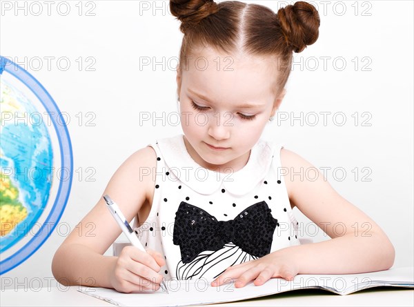 Little girl at the table of a first-grader. Photo taken in the studio