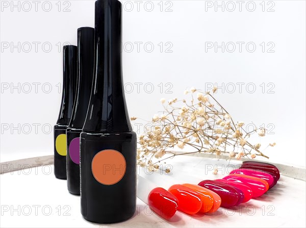 Black bottles of nail polish on a white background with flowers. Manicure design