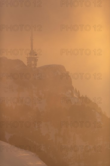 The transmission tower in the fog and warm light of the setting sun