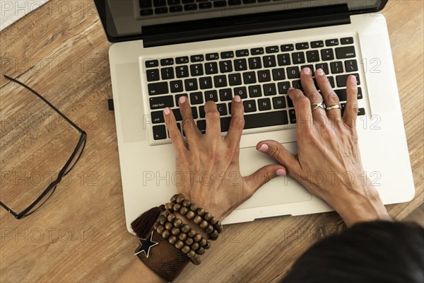 High angle view of the hands of a woman typing on a laptop keyboard