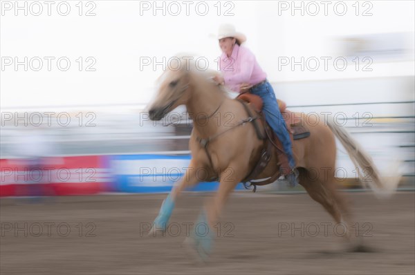 Motion blur of a cowgirl riding fast during barrel racing