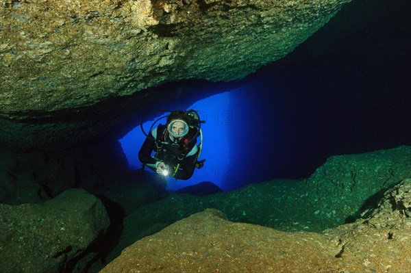 Diver sport diver swims in illuminated cave underwater cave