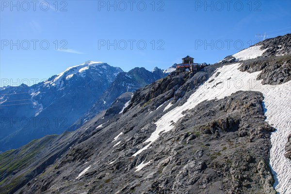 View of tower building Hotel Tibethuette over steep slope at 2800 metres altitude next to pass summit of Stilfser Joch Stelvio