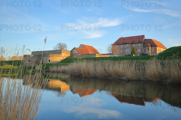 Renaissance moated castle with reflection in the pond and reed grass