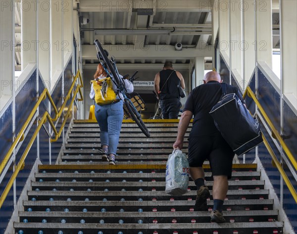 People carrying luggage and bicycle up stairs at railway station