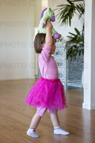 Two year old girl holding her stuffed toy over her head