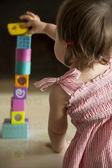 Baby girl skillfully balancing wooden blocks