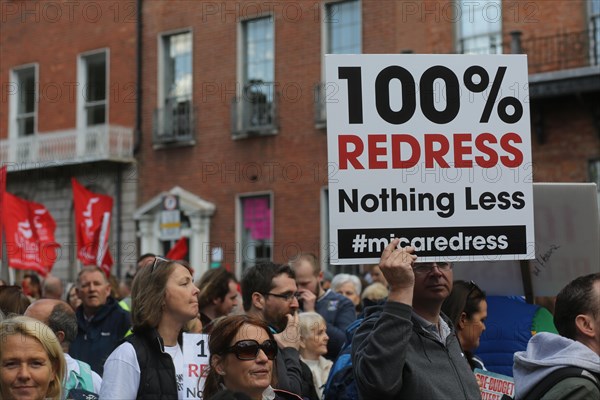 A man holds a placard in the air demanding compensation for the victims of the Mica housing scandal. Dublin