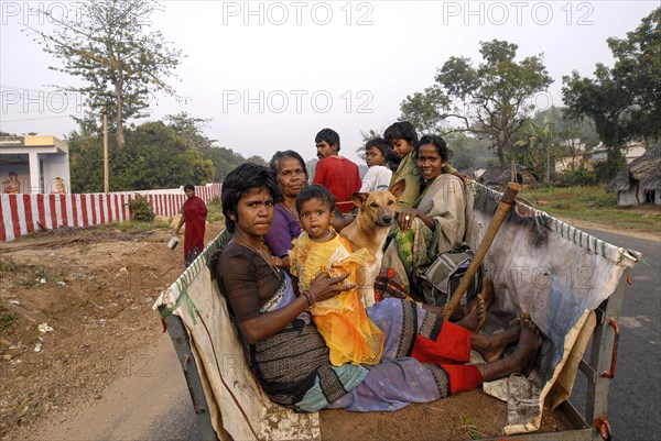 Villagers traveling on a bullock cart with their pet dog