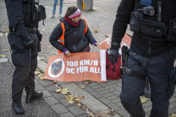 Climate activist of the group Letzte Generation shows poster for speed 100 and 9 euro ticket for all