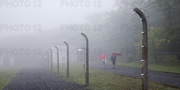 Reconstructed camp fence with people in the fog at beech forest concentration camp