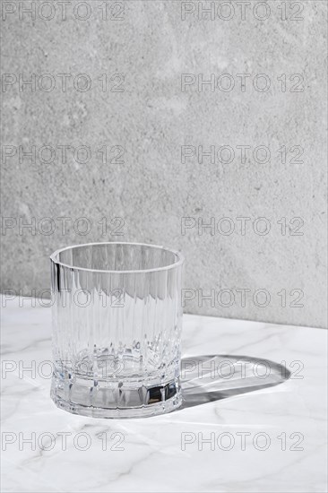 Empty facetted glass over grey background