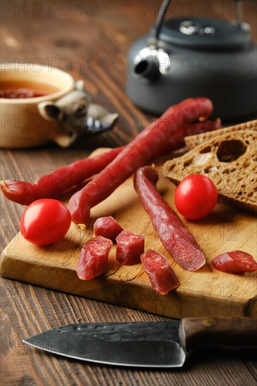 Dry thin pork sausage cut on slices on wooden board