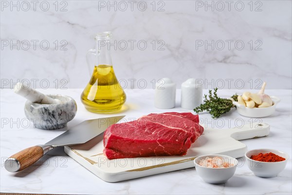 Raw top side beef steak with spice and herbs on kitchen table