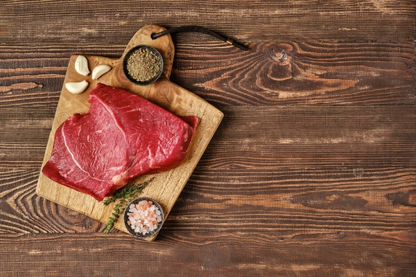 Overhead view of raw top side beef steak on wooden tabletop with place for text