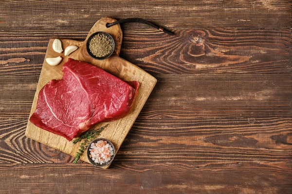 Overhead view of raw top side beef steak on wooden tabletop with place for text