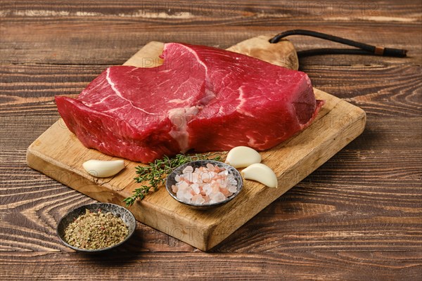 Fresh raw top side beef steak on wooden cutting board ready for barbeque