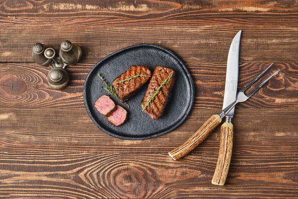 Top view of grilled beef steaks on wooden serving board