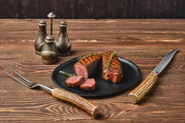 Roasted beef steak cut on slices on black plate