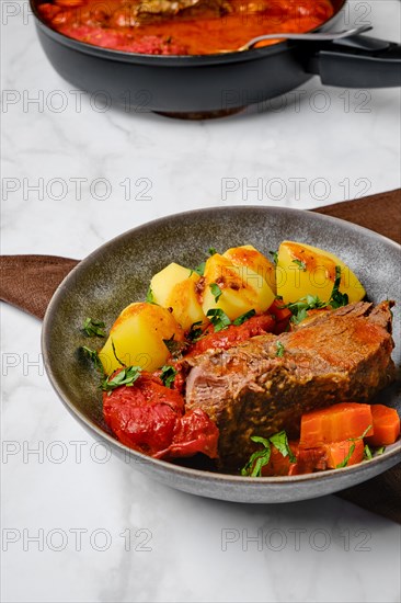 Slow cooking food. Bottom round roast beef meat baked in beer gravy with tomatoes and carrot