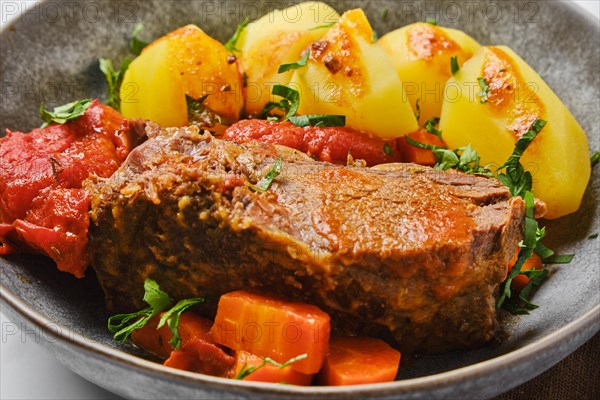 Closeup view of bottom round roast beef meat baked in beer gravy with tomatoes and carrot
